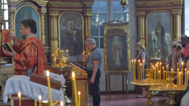 사람들이 스스로 게 트리니티 하루 서비스를 건너 키예프 우크라이나 사제 기도 인테리어 종교 이미지 황금 장식 십자가 아이콘 촛대 읽고 — 비디오