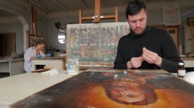 Sanatçılar Dikkatle Simgeleri Restorasyon Kiev Günü Sanat İşçigrubu Sanat Studio Woman Mavi Eldiven Adam Bir Şişe boya alır Boyama vardır
