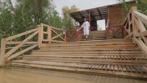 Ritual de Bautismo del Hombre en el Río Jordán Israel El adorador está caminando abajo hacia el pequeño río pantanoso Caña de hierba verde en un banco Árboles forestales de Primavera de Europa — Vídeos de Stock