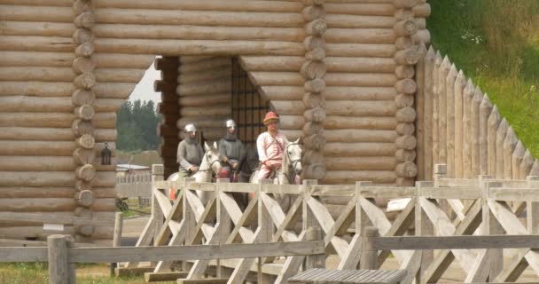 Puerta de madera decorada con elementos forjados están abiertos, pared de la fortaleza, dos caballeros y Primce Vladimir el Grande en un caballo están montando por puente — Vídeo de stock