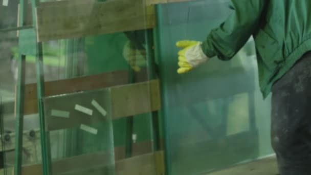 Arbeiter in gelben Handschuhen nahmen die Glasscheibe und legten sie in die Maschine, um eine Fase auf einem Glas zu machen — Stockvideo