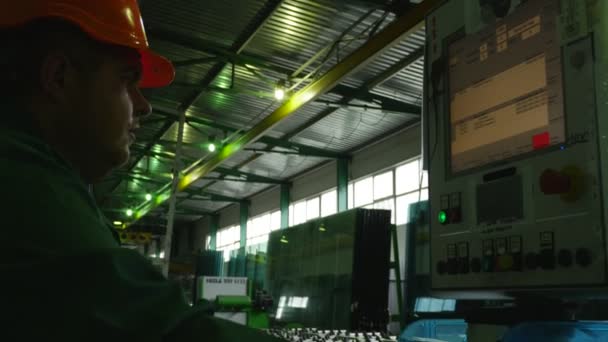 Man, werknemer draait het programma, beweging van het platform met Grab, fabriek van de verwerking van plaat glas op de machines met programma controle — Stockvideo