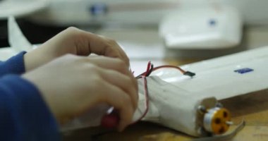 Çocuk Elleri Tel Kesiciler ile Telleri Yumuşatıyor, Elektrik Motoru olan Bir Uçak Modelinde Teller. Çocuk Avia Modelleme Laboratuvarı