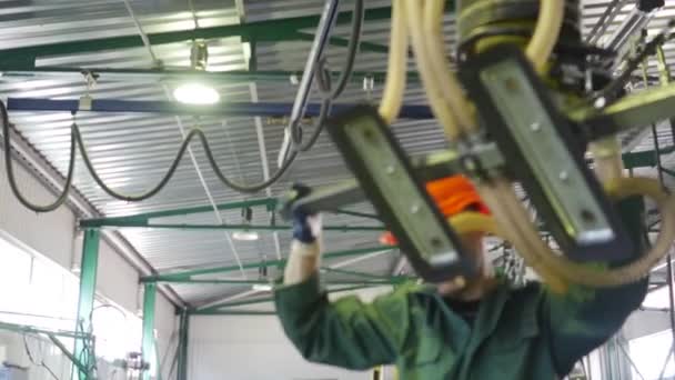 Pracovník v pracovní oděvy s továrně Logo na jeho zpět v oranžová helma používá robota s přísavkami přesunout skelným papírem pro hlazené Workshop okno — Stock video