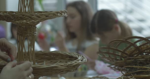 Mujer hace mimbre cesta tres niñas dibujar en Pascua huevos tecnología de pintura en Pascua huevo pintura en la Pascua huevo por el boceto en interiores — Vídeo de stock