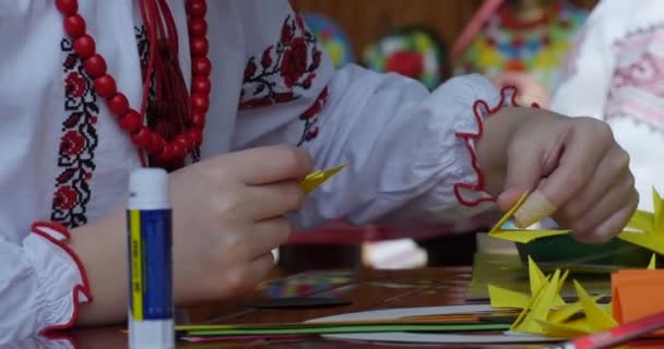 Girl In Vyshyvanka And Red Beads Makes Origami Paper Origami Tube Of Glue And Colored Paper On Table Kids Make Origami Origami Contest Making Of Kusudama — Stock Video