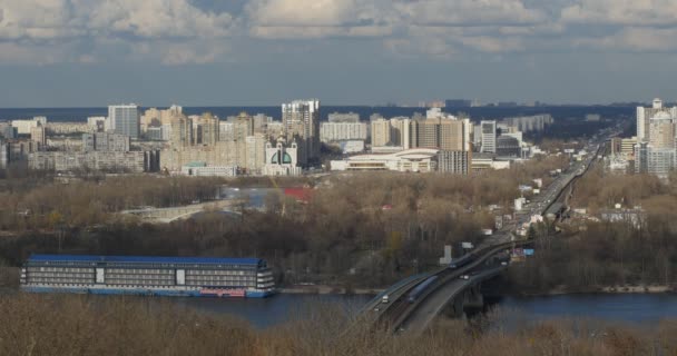 Kiev Ucrania Ribera izquierda del Dnieper Metro Puente Hydropark Edificios cerca de la estación de metro Livoberezhna Primavera Temprana Soleado Día Cielo Azul Cumulus Nubes — Vídeos de Stock