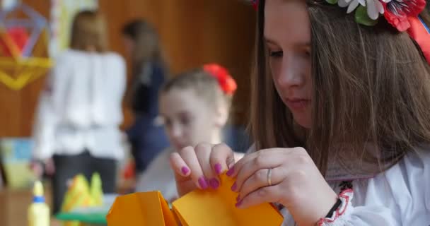 Lány a Vyshyvanka és ideiglenes tákolmány Origami a gyerekek narancssárga papír Origami Origami verseny így Kusudama Origami moduláris egység Origami közeli össze, hogy — Stock videók