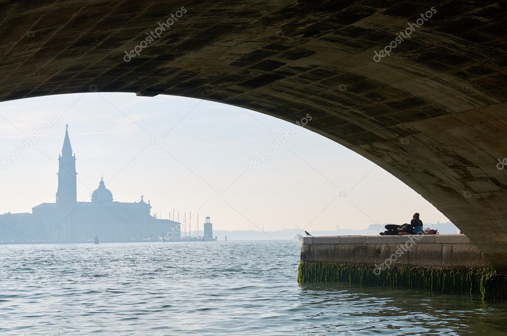 View on a Venice church with two lovers under a bridge