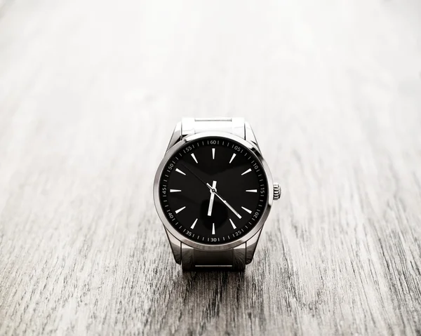 Silver reflective wrist watch with black dial on wood surface — Stock Photo, Image