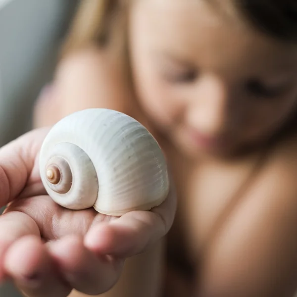 Girl, embarassed offering a white snail shell 