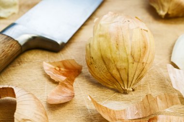 Onion peelings, knife and wood cutting board in the background