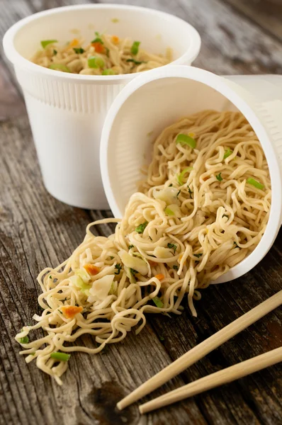 Instant noodles pasta ramen spilled on rustic wood table