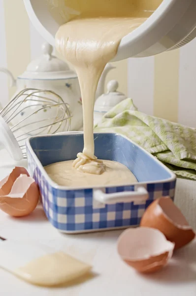 Ev yapımı yoğurt sünger kek hamuru mavi seramik tabak içinde dökülür