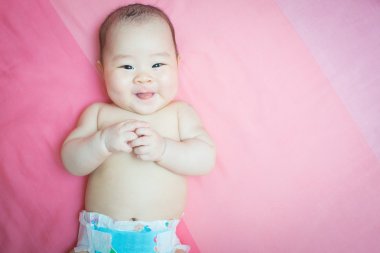 Asya bebek kız gülümseme pembe yatak