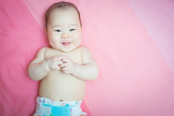 Asya bebek kız gülümseme pembe yatak — Stok fotoğraf