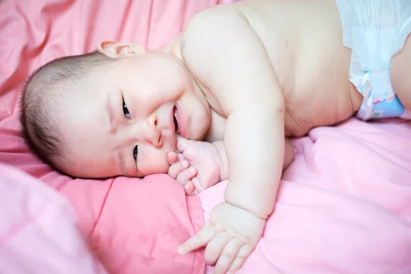 Aziatische babymeisje huilen op roze bed — Stockfoto