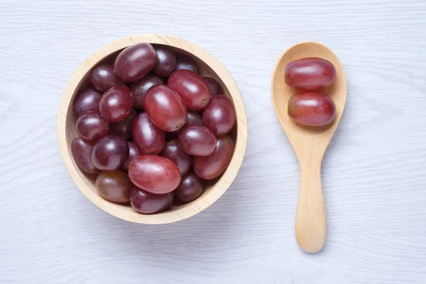 Uvas rojas en cuenco de madera y cuchara — Foto de Stock