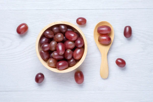 Uvas rojas en cuenco de madera y cuchara — Foto de Stock