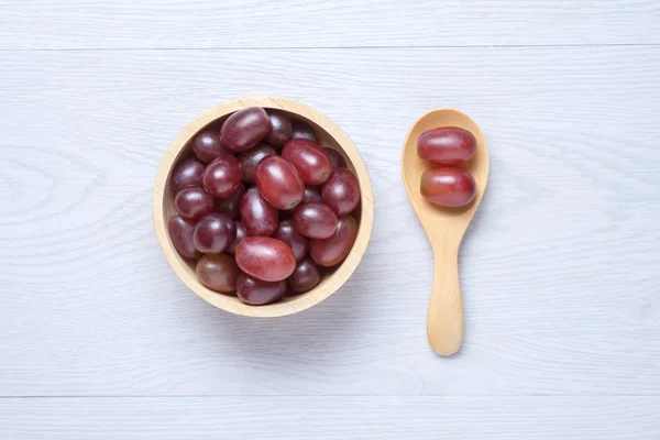 Raisins rouges dans un bol et une cuillère en bois — Photo