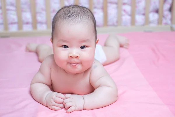 Asiatische baby Mädchen liegen anfällig auf rosa Bett — Stockfoto