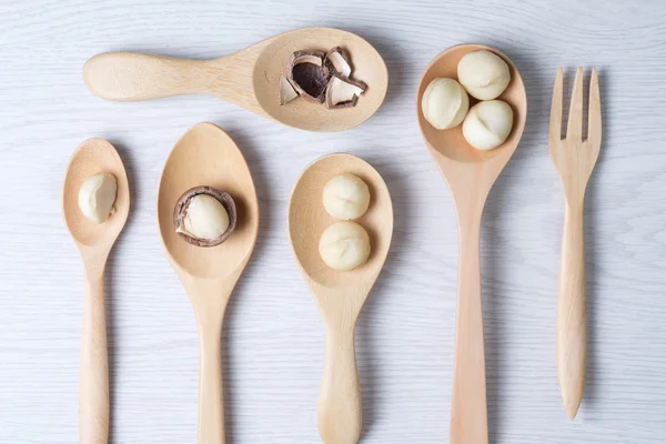 Top view macadamia nuts and shell in wooden spoons — Stock Photo, Image