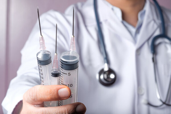 Doctor holding syringes