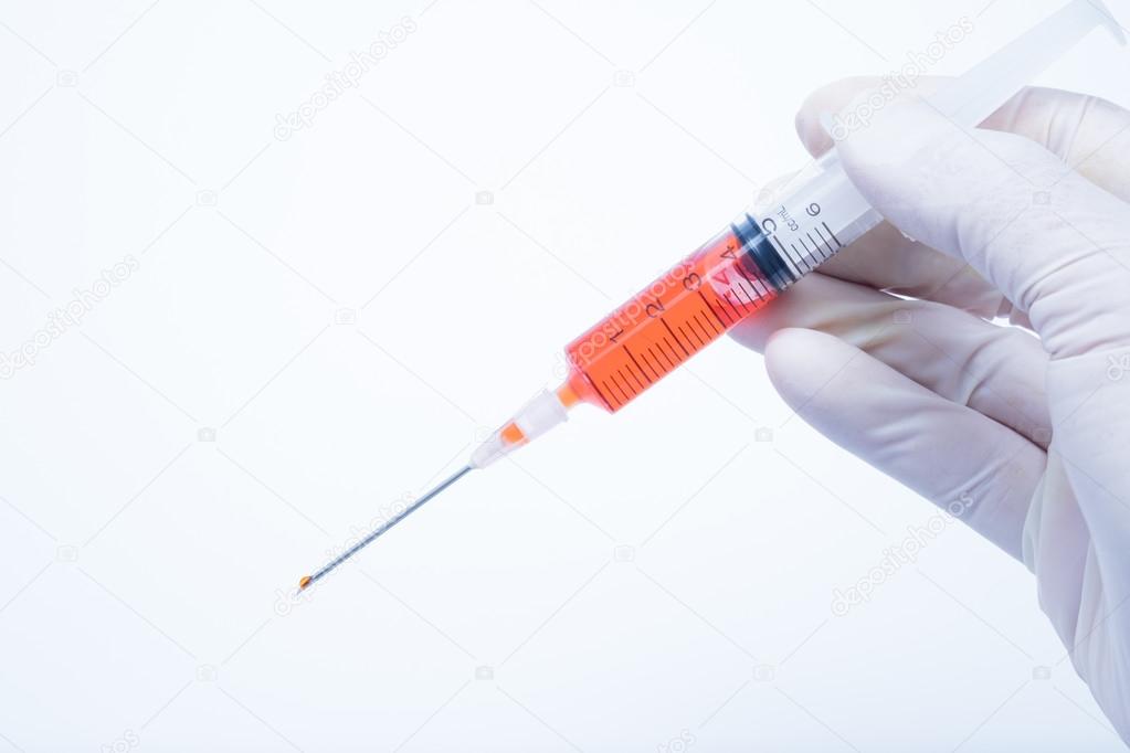 hand holding red vaccine syringe