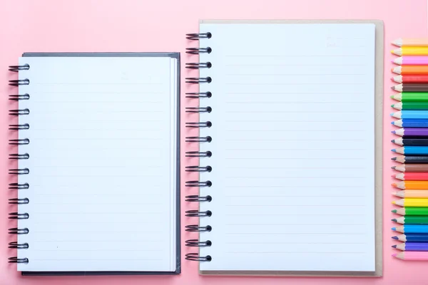 笔记本和彩色的铅笔在粉红色的背景上 — 图库照片