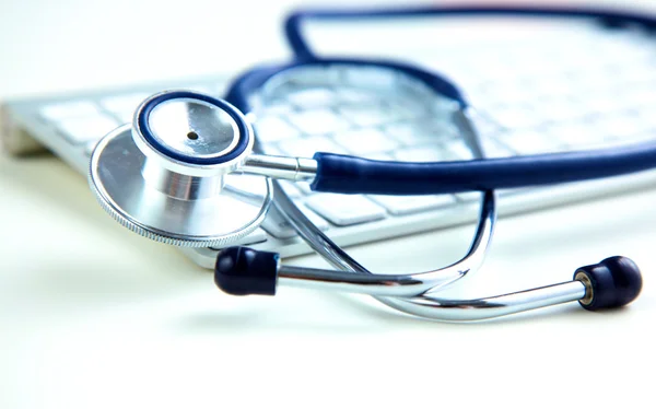 Um estetoscópio médico perto de um laptop em uma mesa de madeira, em branco — Fotografia de Stock