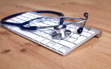 Beyaz ahşap bir masa üstünde a laptop yanında sağlık stetoskop