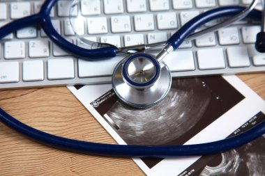 Beyaz ahşap bir masa üstünde a laptop yanında sağlık stetoskop