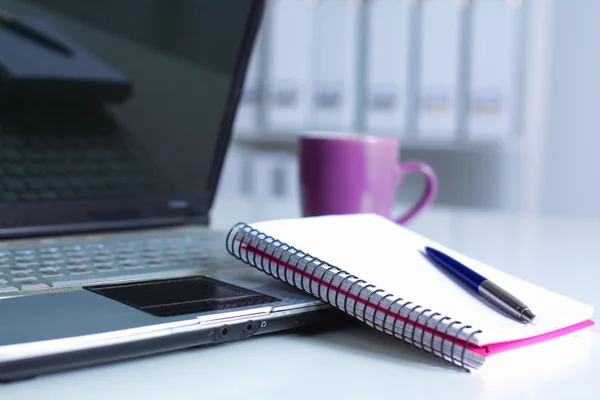 Mesa de escritório com bloco de notas em branco e laptop — Fotografia de Stock