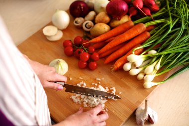 Mutfakta sebze doğrayan genç bir kadın.