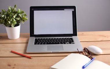 Laptop ahşap bir masada duruyor.