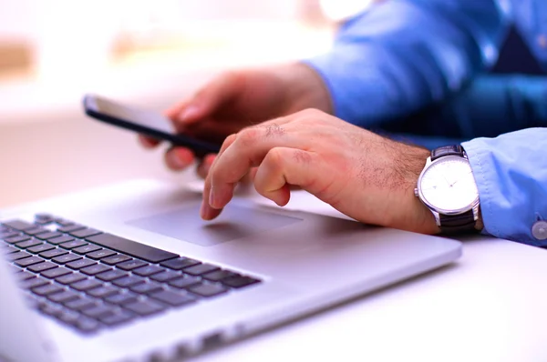 Businessman at a table with a smartphone and a laptop — Stock Photo, Image