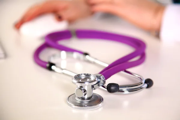 Stethoscope in the foreground, in the background arms — Stock Photo, Image