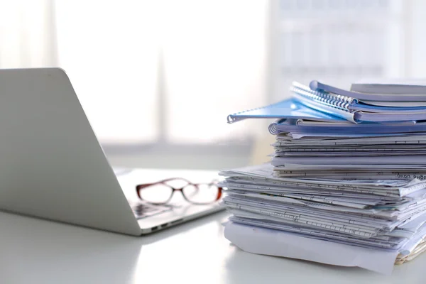 Laptop com pilha de pastas na mesa sobre fundo branco — Fotografia de Stock