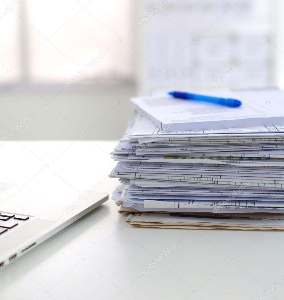 Laptop with stack of folders on table on white background