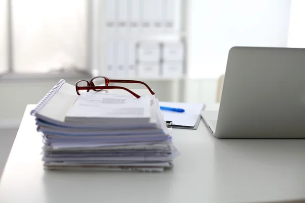 Laptop com pilha de pastas na mesa sobre fundo branco — Fotografia de Stock