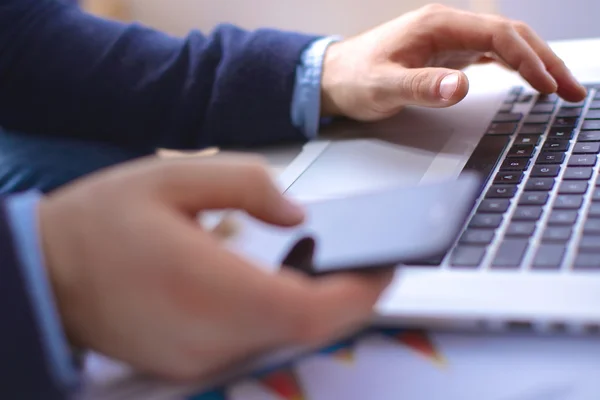 Businessman at his workplace uses a smartphone and laptop — Stock Photo, Image