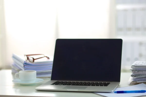 Laptop with stack of folders on table on white background Stock Photo