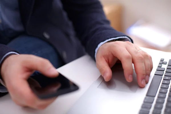 Businessman at his workplace uses a smartphone and laptop — Stock Photo, Image