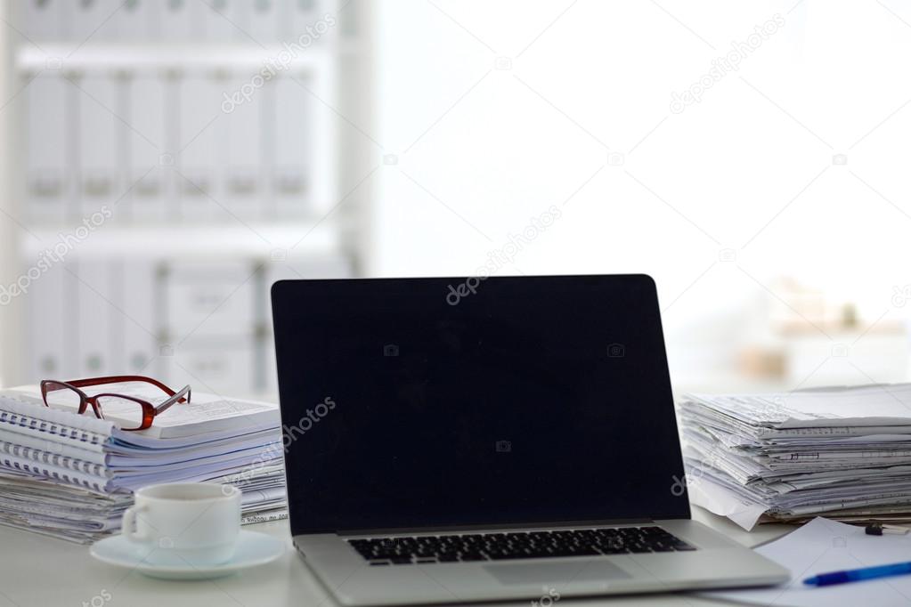 Laptop with stack of folders on table on white background