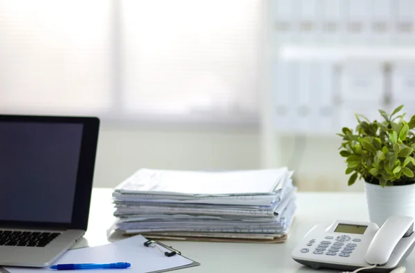 Laptop with stack of folders on table on white background