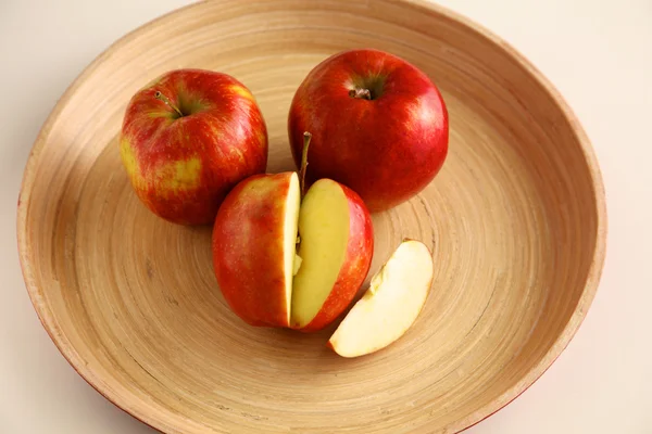 Mele rosse su un piatto di legno sul tavolo — Foto Stock