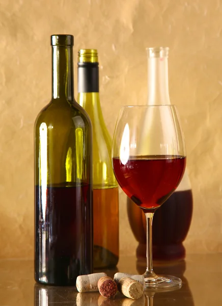 Şarap şişesi ve cam masa üzerinde şarap kadehi — Stok fotoğraf