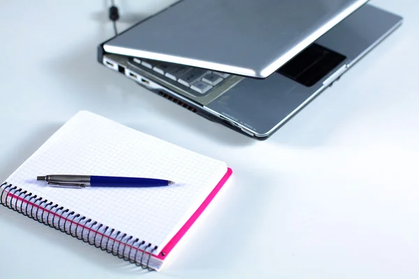 Laptop with stack of folders on table on white background Stock Picture