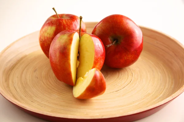 Rote Äpfel auf einem Holzteller auf dem Tisch — Stockfoto