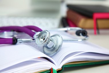 Bir dizüstü bilgisayar arka plan ve kitaplar yatan stetoskop